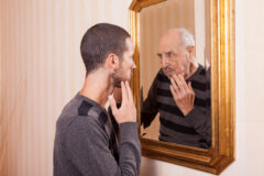 young man looking at an older himself in the mirror