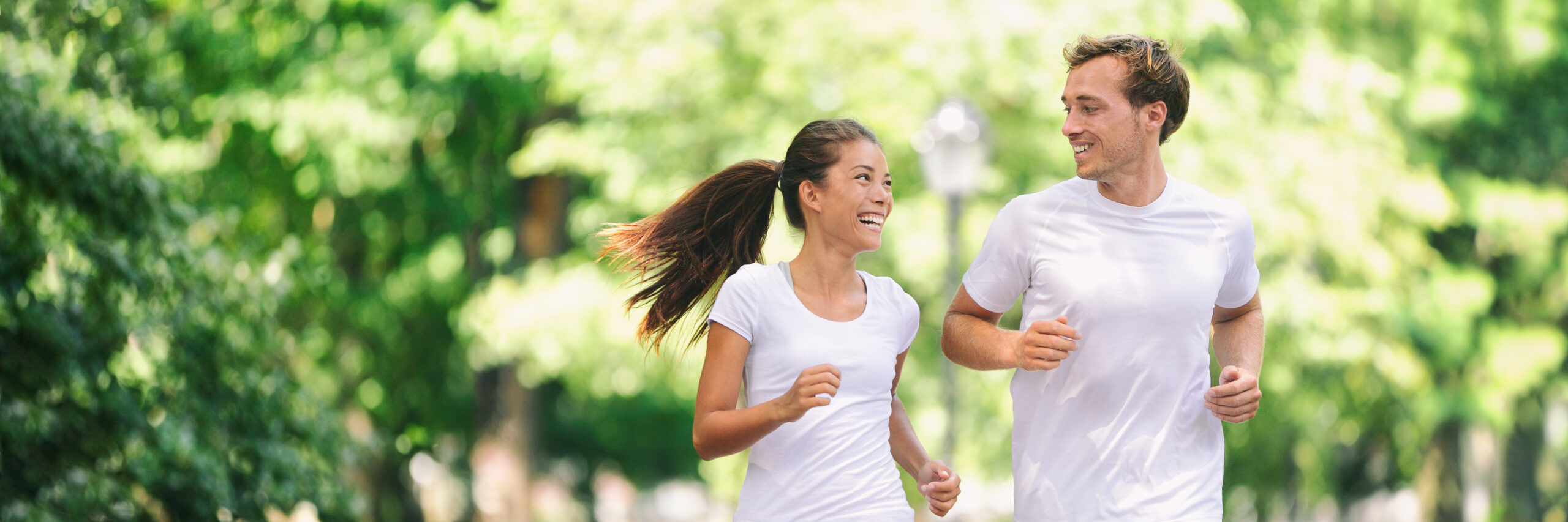 Run exercise fitness friends walking running talking together on fun race in city park panoramic banner background Healthy active lifestyle young people, Asian woman, Caucasian man couple